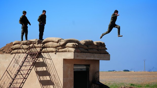 Three young YPG fighters prepare to leap from their lookout near the village of Tel Marouf, freed from the Islamic State two days before. 