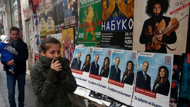 People walk in front of posters of Bulgarian Socialists Party candidate Rumen Radev in Sofia, Bulgaria.