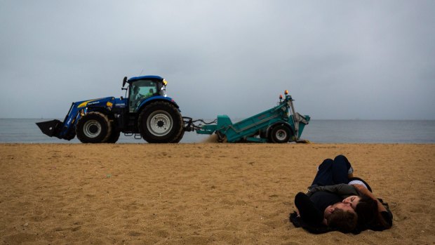 A partygoer sleeps on St Kilda beach as the post- New Year's Eve clean-up begins on Sunday.