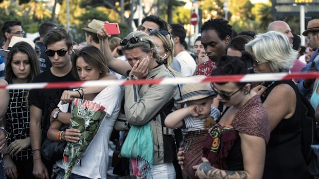 People react as they gather at a makeshift memorial near the scene of the carnage in Nice.