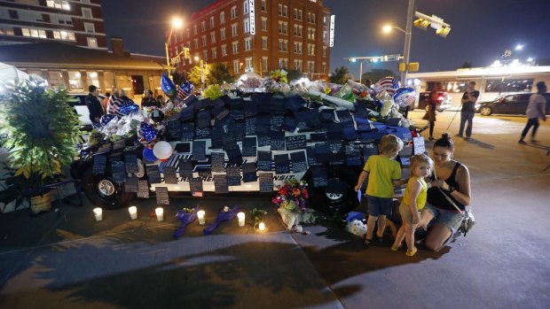People visit police cars decorated as a public memorial in front of Dallas police headquarters.