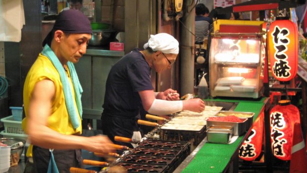 Osaka street vendors preparing fried octopus balls (takoyaki).