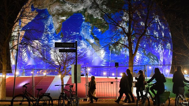 People pass the German pavilion in the shape of the earth during the COP 23 Fiji UN Climate Change Conference.