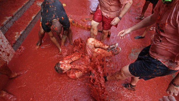 A man lies in a puddle of squashed tomatoes during the annual Tomatina food fight in Bunol, 50km from Valencia, Spain.