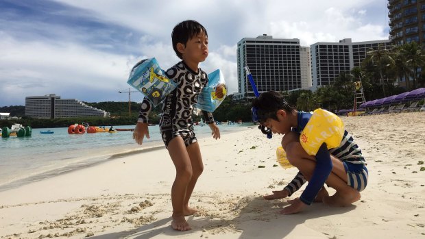 Children play in the sand in Tumon, Guam, the small US territory North Korea has threatened to attack.