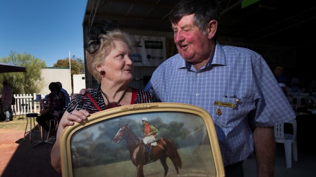 Community stalwarts: Maree and Des Ryan at the centenary Manangatang Cup race meeting, holding a portrait of jockey Roy Higgins winning at Manangatang spring races on the horse Voltain in 1957. 