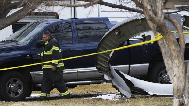 A firefighter walks past a large piece the United Airline plane's engine housing that fell in the suburbs of Denver.