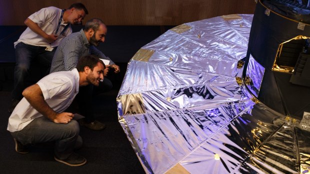 Scientists look under a scaled reproduction of the GAIA surveyor after an event of the European Space Agency to release the first data on its GAIA mission to make a space map.
