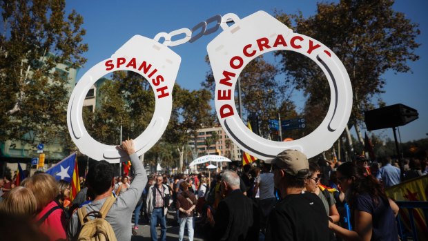 Protesters hold fake handcuffs as they take part a rally outside the Catalan parliament in Barcelona.
