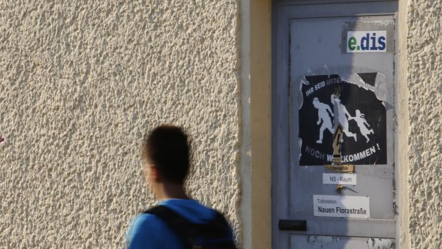 A boy walks past a torn poster that reads "You are neither refugees nor are you welcome" in Nauen, eastern Germany.