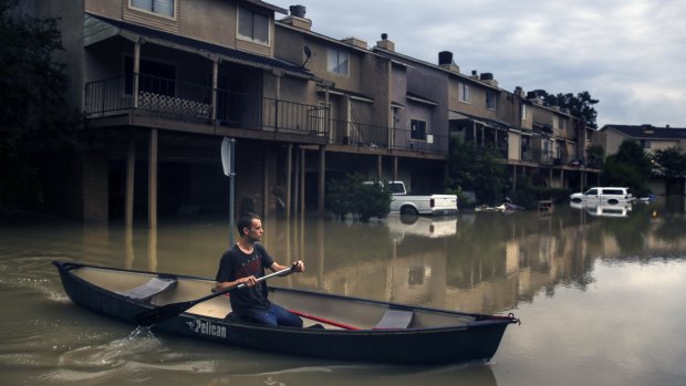 Chance Morgan canoes past flooded townhouses as he tries to get to his home.