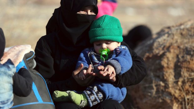 A Syrian woman holds a child at the refugee camp. 