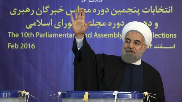 Iranian President Hassan Rouhani waves to media after casting his vote in Tehran, Iran, on Friday.