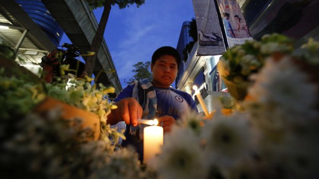 A man lights a candle near the Erawan Shrine at Ratchaprasong intersection the day after the explosion.