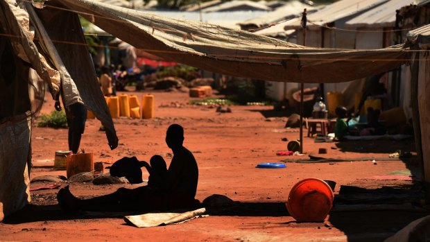A woman nurses a child in the shade of her makeshift home at the Juba Protection of Civilians site.