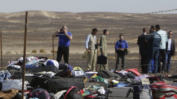 Russian investigators stand near debris, luggage and personal effects of passengers a day after a passenger jet bound for St. Petersburg in Russia crashed in Hassana, Egypt.