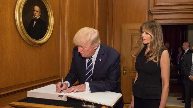 US President Donald Trump, accompanied by first lady Melania Trump, signs the Supreme Court guest book, on Thursday.