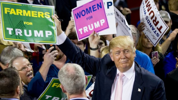 Republican presidential candidate Donald Trump holds up a campaign sign that reads "Farmers for Trump" after speaking at a rally at Valdosta State University in Valdosta, Georgia.