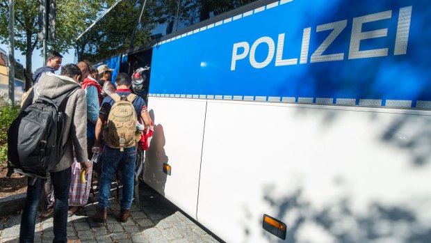 Migrants and refugees board a police bus after their arrival at the train station in Passau, southern Germany.