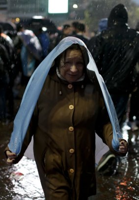 A woman covers herself with an Argentine flag under the pouring rain.
