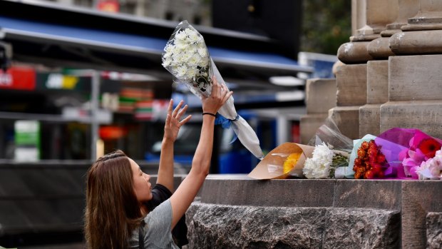 Passers-by lay flowers at the scene of yesterday's Bourke Street Mall tragedy.