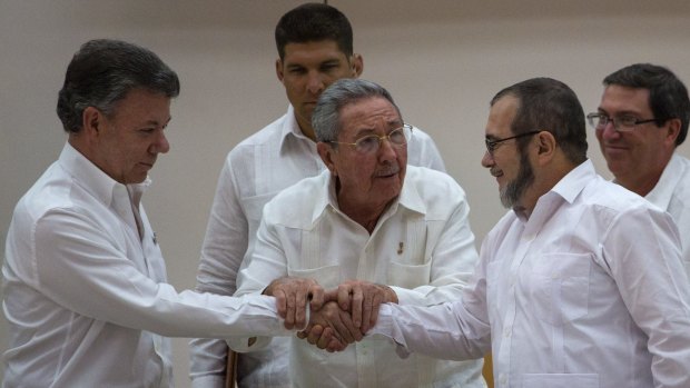 Cuba's President Raul Castro, centre, encourages Colombian President Juan Manuel Santos, left, and the commander the Revolutionary Armed Forces of Colombia, or FARC, Timoleon Jimenez, known as  "Timochenko", to shake hands in Havana on Wednesday.