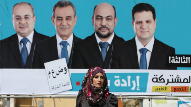 A woman walks past a Joint List billboard in the town of Umm al-Fahm.