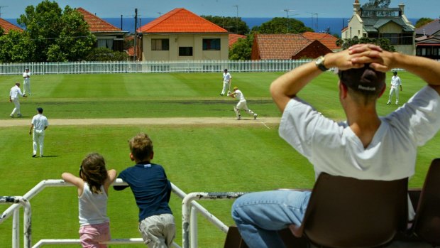 Clayton McBride, 8, and his sister Cordelia, 4, enjoying the cricket, while their dad, Slide, looks on during a match between University of NSW and Eastern Suburbs at Waverly Oval in Bondi. 