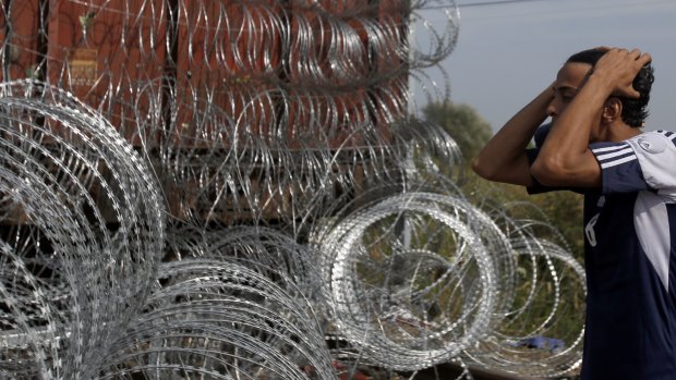 A migrant looks and reacts at the closed railway border crossing between Serbia and Hungary, near Horgos, Serbia, on Tuesday.