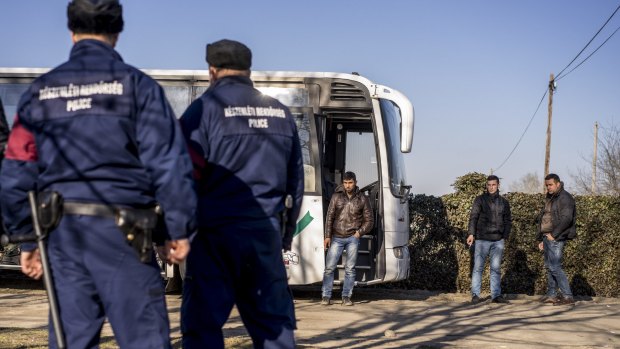 Two Kosovar Albanians and an Afghan man smoke after their bus was stopped by police crossing the border from Serbia, in Assothalom, Hungary.
