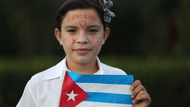 A child stands on the side of the road as she awaits the arrival of a military convoy with the flag-draped chest containing the remains of Fidel Castro.