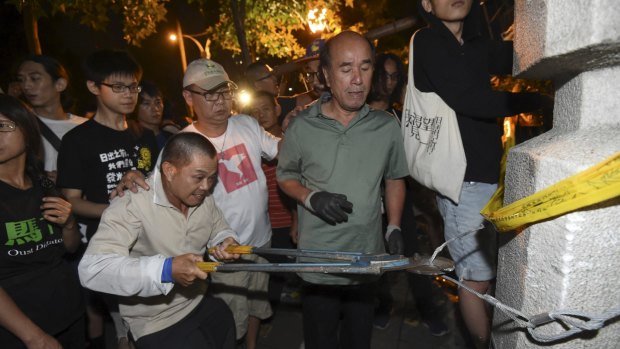 A man cuts a wire as protesters push down a barricade to enter the Ministry of Education in Taipei in the early hours of Friday.