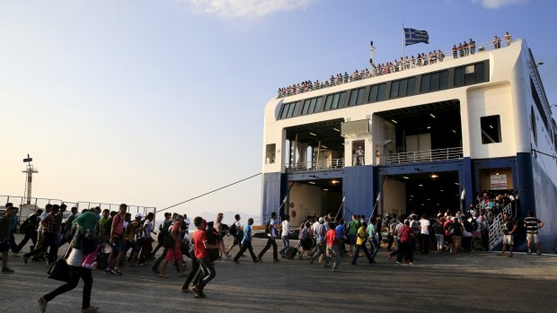 Migrants and refugees with temporary documents and a few tourists run to embark a ferry bound for Athens on the Greek island of Kos on Monday.