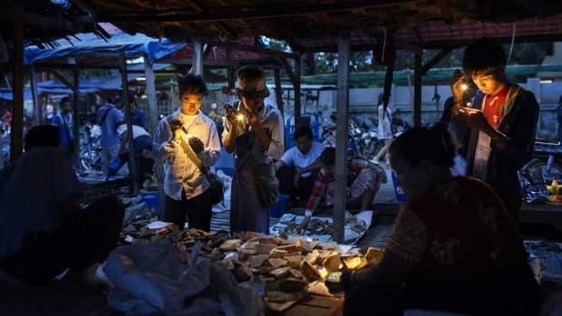 Burmese dealers use flashlights to check the quality of jade at a market in Mandalay, Myanmar last year.