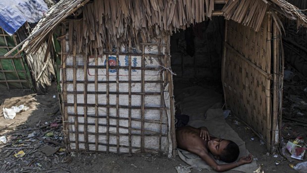 A Rohingya boy naps in his family's temporary shelter next to an internal displacement camp in Sittwe, Burma, in May.