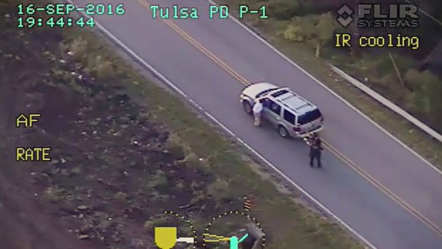 Terence Crutcher, left, lowers his right arm as he is pursued by police officers moments before he was shot and killed.