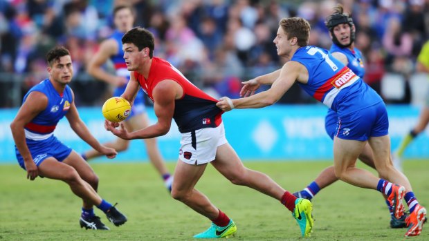 MELBOURNE, VICTORIA - FEBRUARY 18: Angus Brayshaw of the Demons handballs away from Lachie Hunter of the Bulldogs during the 2017 JLT Community Series match between the Western Bulldogs and the Melbourne Demons at Whitten Oval on February 18, 2017 in Melbourne, Australia. (Photo by Michael Dodge/AFL Media/Getty Images)