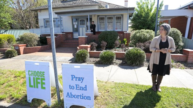 A protester stands outside the Fertility Control Clinic in Albury. A security guard mans the door to protect women entering.