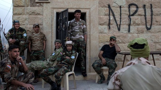 Fighters from the NPU relax at their check point base inside a destroyed Qaraqosh church on November 8.