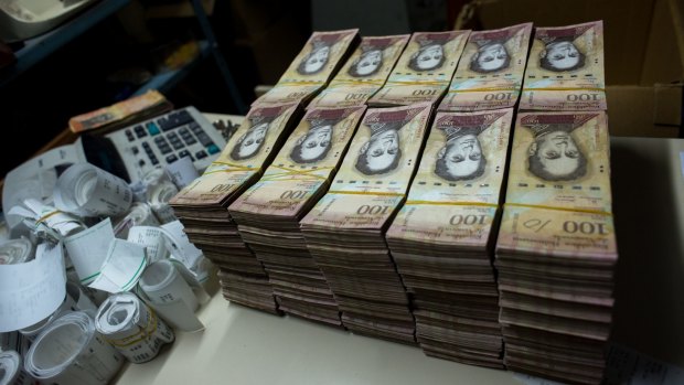 Stacks of banknotes are piled on a desk in a bakery in Caracas. Once one of the world's strongest currencies, the bolivar has been reduced to nuisance status.