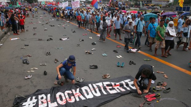 Protesters scatter pairs of slippers and shoes to symbolise victims of President Rodrigo Duterte's "war on drugs".