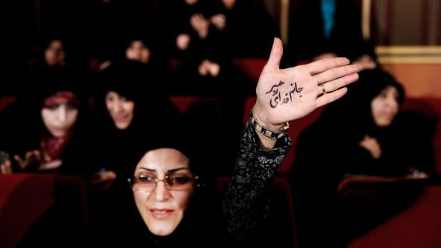 An Iranian hardliner raises her palm with Persian writing that reads: "I'm ready to sacrifice myself for the Supreme Leader," during an anti-British campaign claiming reformist rivals were backed by the BBC and the British government.