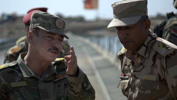 Iraqi Major-General Najim al-Jabbouri, left, talks to an officer on a temporary pontoon bridge near Qayara Air Base, northern Iraq, ahead of the Mosul offensive.