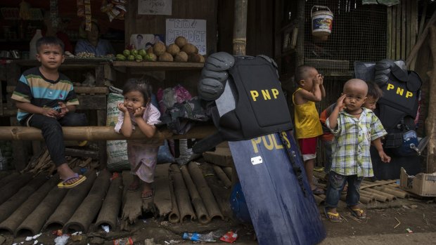 Police gear and shields near  children displaced from the besieged city of Marawi. Evacuees report of worsening conditions inside evacuation centres as the conflict drags on.