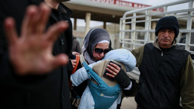 A Syrian woman carrying her baby walks after she crossed into Turkey on Saturday at a border crossing near Hatay, in Turkey's south-east.