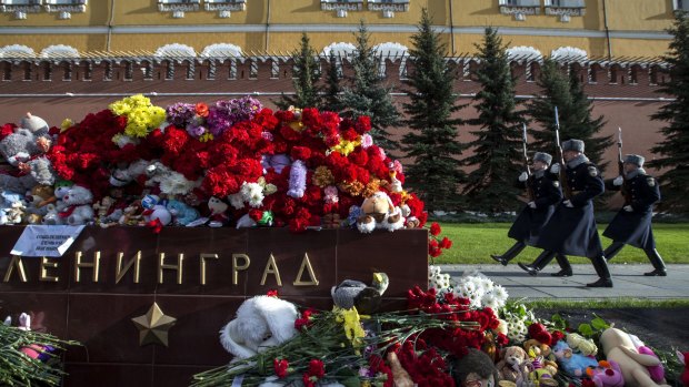 The Kremlin guards pass flowers and toys laid at the memorial stone with the word Leningrad (St Petersburg) at the Tomb of the Unknown Soldier outside Moscow's Kremlin Wall on Tuesday.