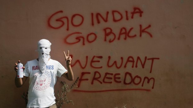 A masked Kashmiri protester shows victory sign after drawing a graffiti on the wall of a building in Srinagar, Indian controlled Kashmir.