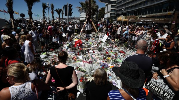 People gather and lay tributes on the Promenade des Anglais in Nice. 