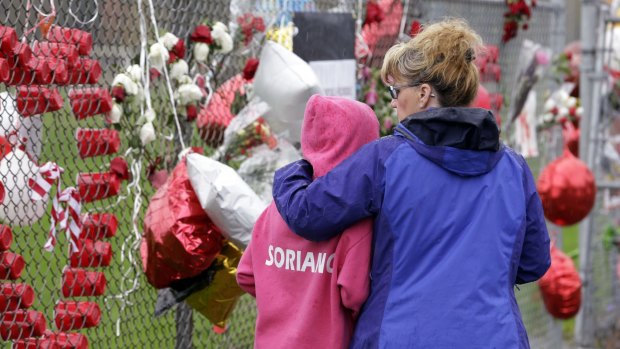 Gabby Soriano, 11, is embraced by her mother, Gay, as they visit a memorial to the school shooting victims. Gabby's cousin, Gia, was among those killed.