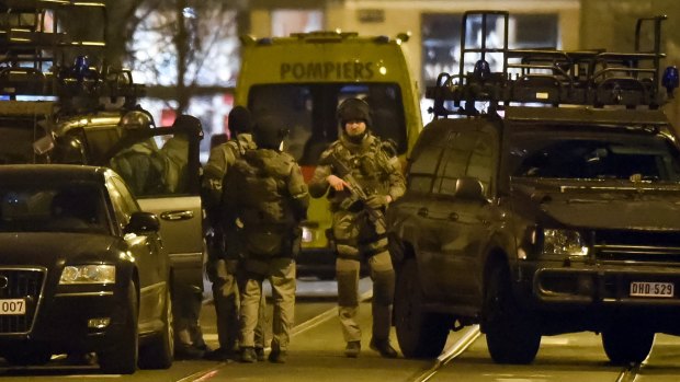 Special operations police take positions during a raid in Brussels on Tuesday where one man was killed. Police say two others are on the run.